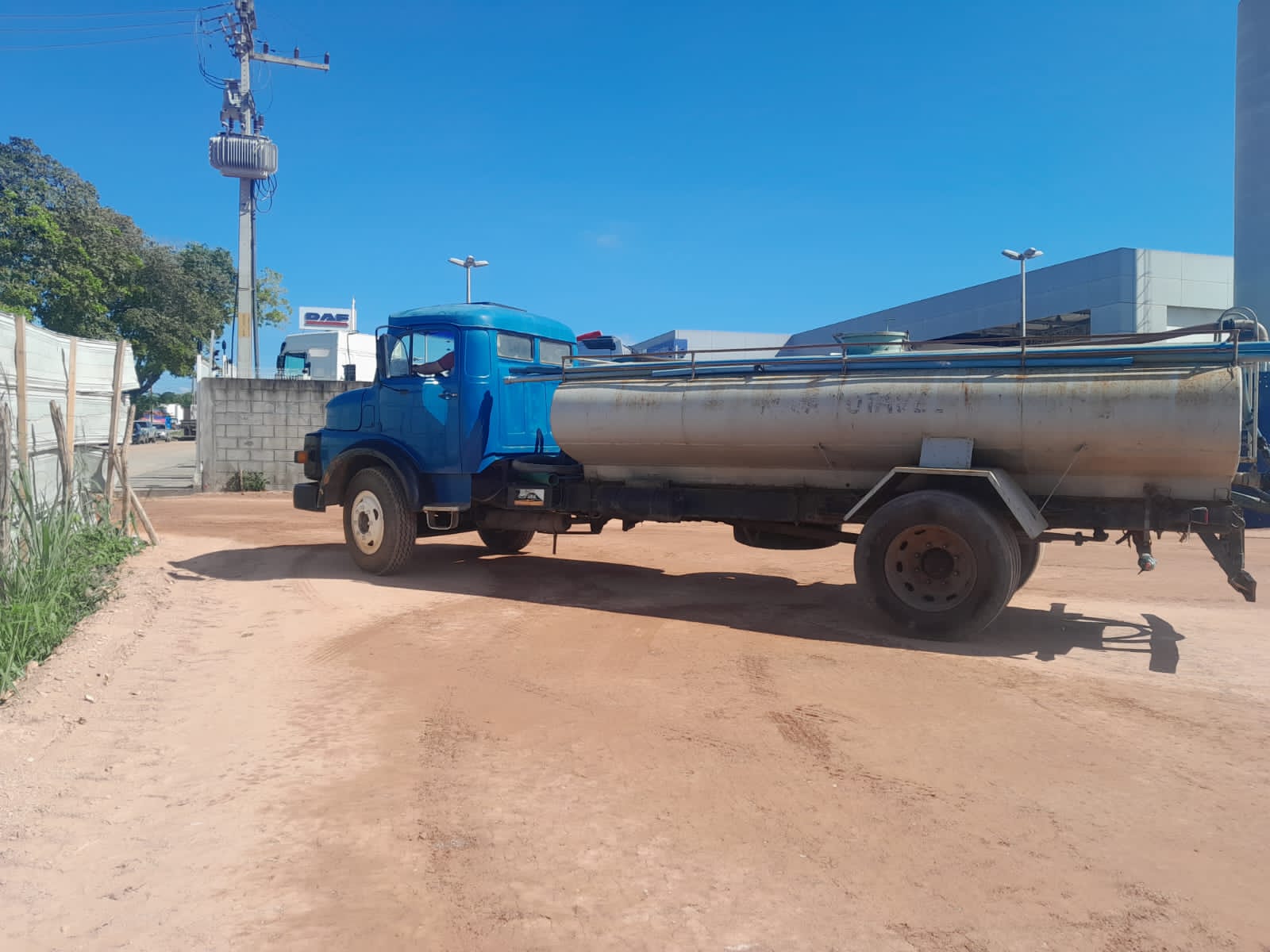 Caminhão-tanque azul estacionado em pátio de terra